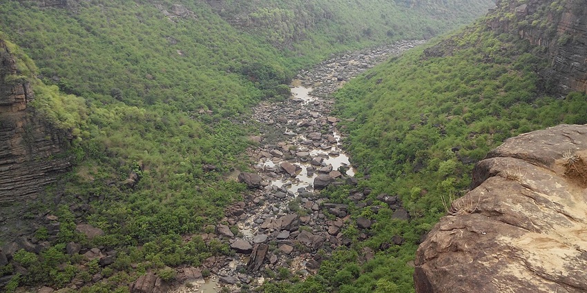 A picture of a lush green valley in Rewa with a tranquil waterfall cascading nearby