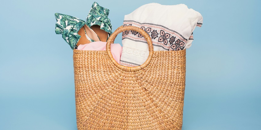 A basket filled with neatly arranged, colourful towels, perfect for relaxing at the beach.