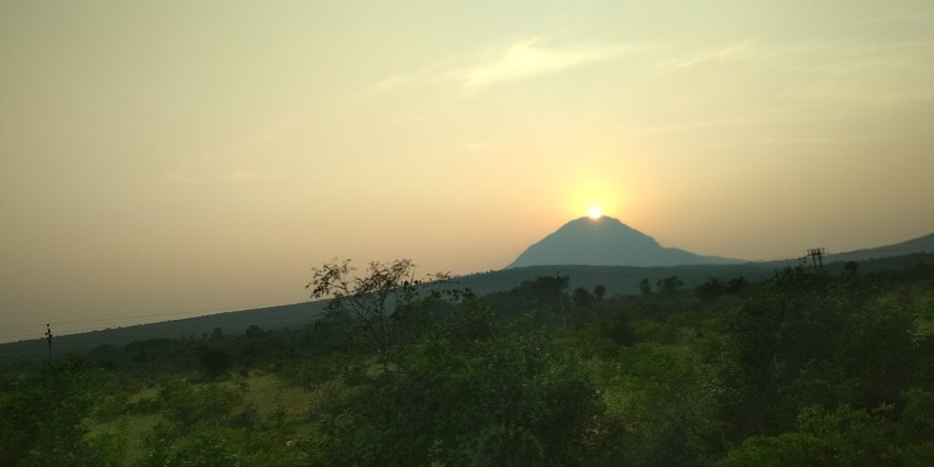 Serene view of a sunset on top of the Udayagiri hills surrounded by lush greenery.