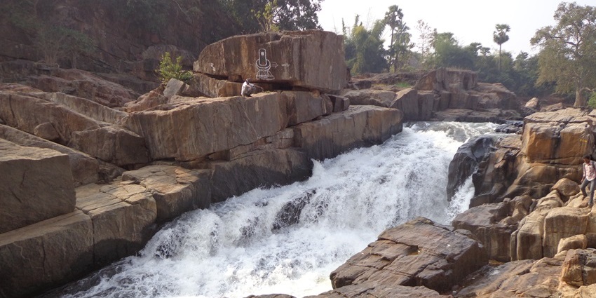 A picture of a scenic waterfall slowly cascading down a rocky terrain amidst lush greenery