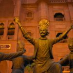 A view of sculptures doing bhangra in front of a majestic tourist attraction in Punjab.