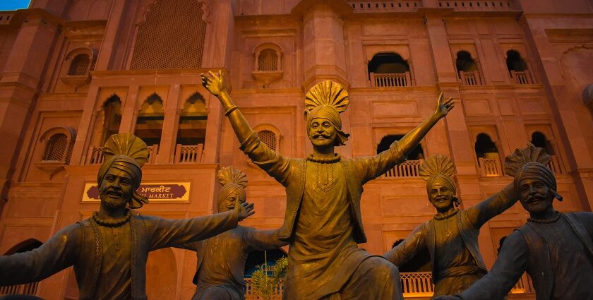 A view of sculptures doing bhangra in front of a majestic tourist attraction in Punjab.