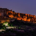 A serene glimpse of a palace brimming with yellow lights after the sun has set down.