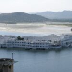 A vibrant view of Udaipur’s Lake Pichola with a traditional boat, one of the freshening places to visit in Rajasthan in June.