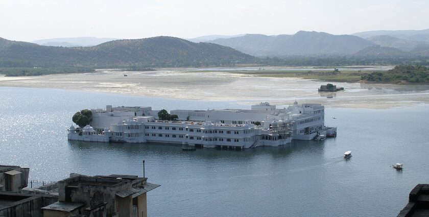 A vibrant view of Udaipur’s Lake Pichola with a traditional boat, one of the freshening places to visit in Rajasthan in June.