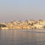 A stunning sunset view over Lake Pichola with serene waters and historic buildings, one of the best places to visit in Udaipur in October.