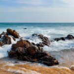 A view of a brown rocky shore at one of the beaches under blue sky during daytime.