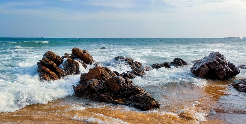 A view of a brown rocky shore at one of the beaches under blue sky during daytime.