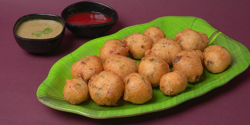 Image of a full plate Punugulu with green chutney and red chutney on the side served.