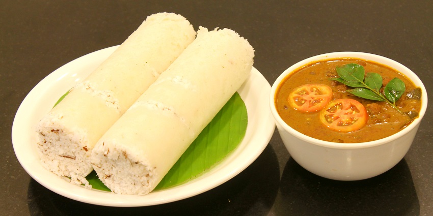 A plate of puttu served with kadala curry, showcasing traditional South Indian cuisine.