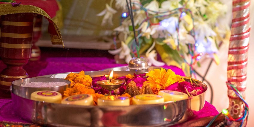 A beautifully arranged Pooja Thali with vibrant flowers, candles, and traditional offerings.