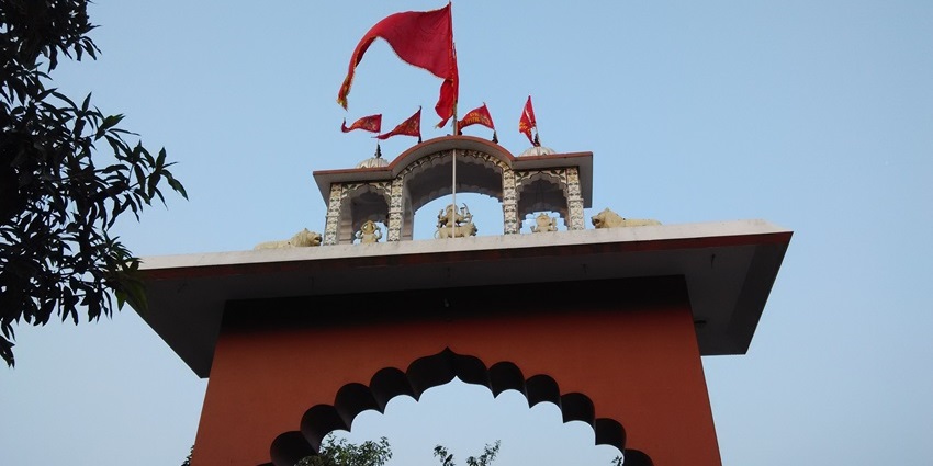 An image of a temple top with a flag waving similar to the Pracheen hanuman temple