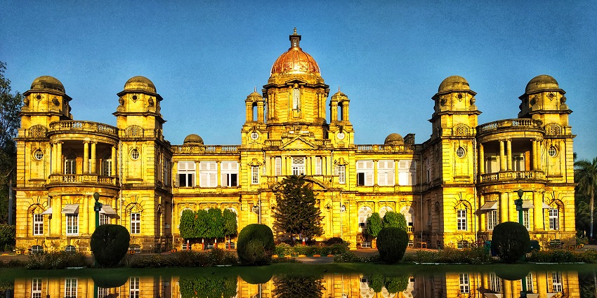 A picture of a beautiful palace taken during nighttime, with its reflection falling in the pond in front