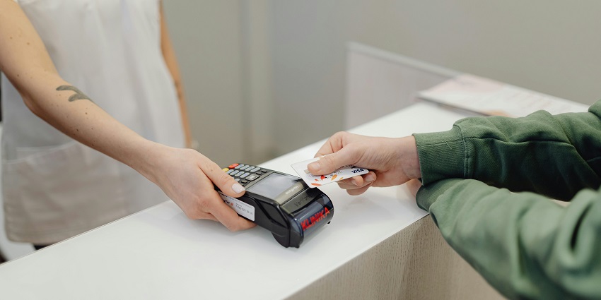 A person holding his card to the digital payment machine and other person holding machine.