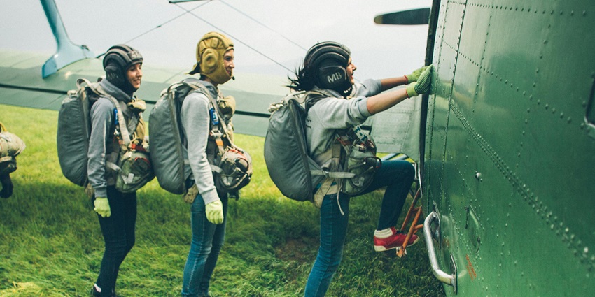 Smiling skydivers boarding a plane, excited for their upcoming skydiving adventure.