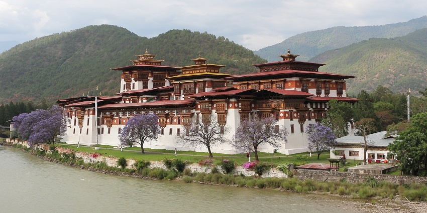 Places to travel in Bhutan in May include the majestic Punakha Dzong, beautifully set against a serene river and mountains.