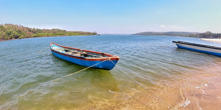 A glimpse of the serene waters of Querim Beach decked with boats on the shoreline.