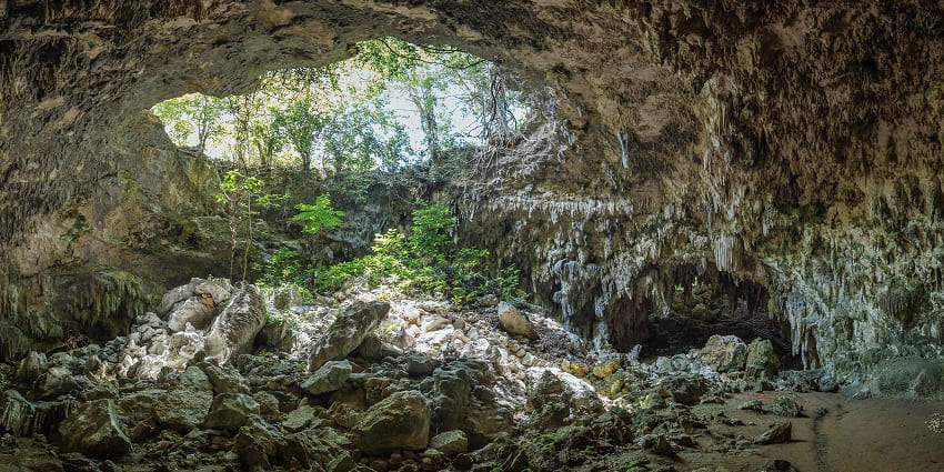 A rugged cave entrance surrounded by natural rock formations, inviting adventurous travellers, one of the tourist attractions in Arambol.