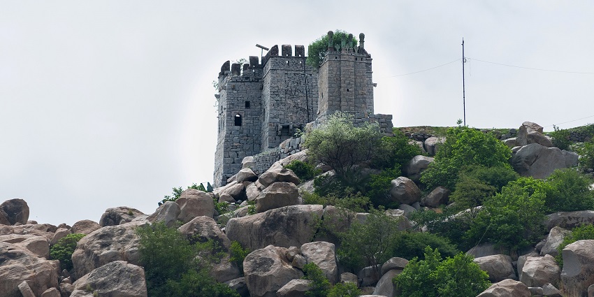 Ancient Raichur stone fort perched atop a rocky hill, surrounded by lush greenery