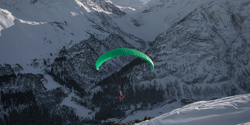 An astonishing view of a person gliding through the snow-clad mountains in Raison.