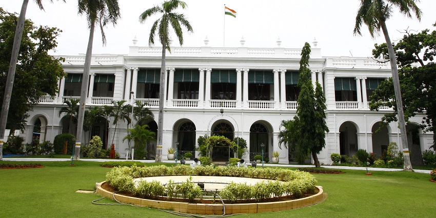 A grand heritage palace with red sandstone architecture, surrounded by lush gardens, one of the places to visit near Bharatpur.