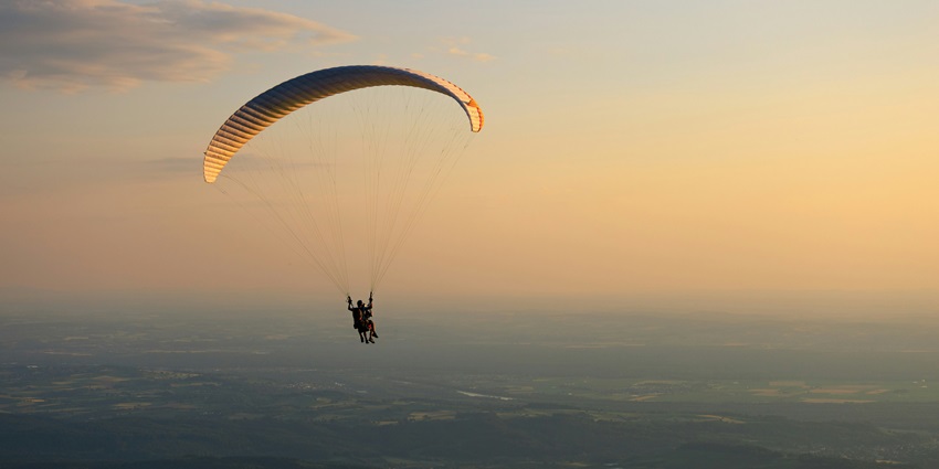 A breathtaking view of people enjoying an adventure sport during the sunset in the sky.