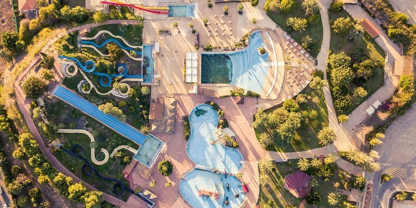An aerial view of a place for fun with swimming pools, slides, and lush greenery.
