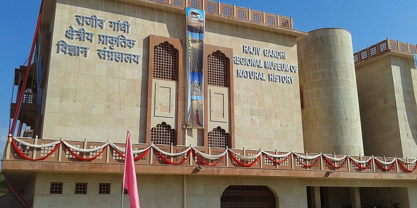 A frontal view of a regional museum with a lush green garden surrounding it