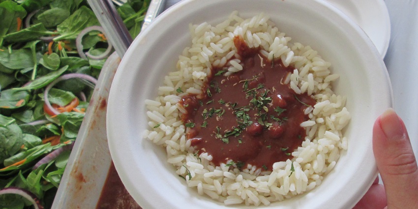 An image of rajma served over steamed rice (chawal), garnished with onions and cilantro.