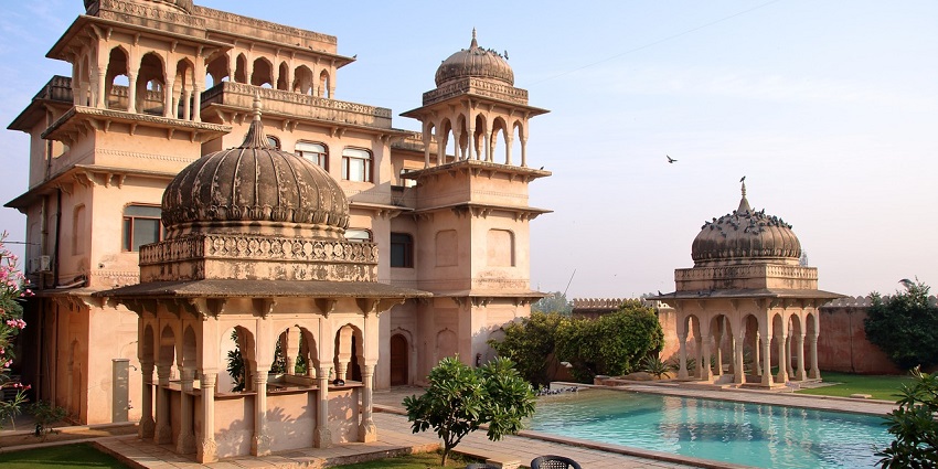 A view of a grand palace, now functioning as a hotel, with intricate Indian architectural details.