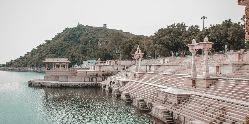 Scenic view of Rajsamand Lake, with calm waters reflecting the surrounding hills and sky.