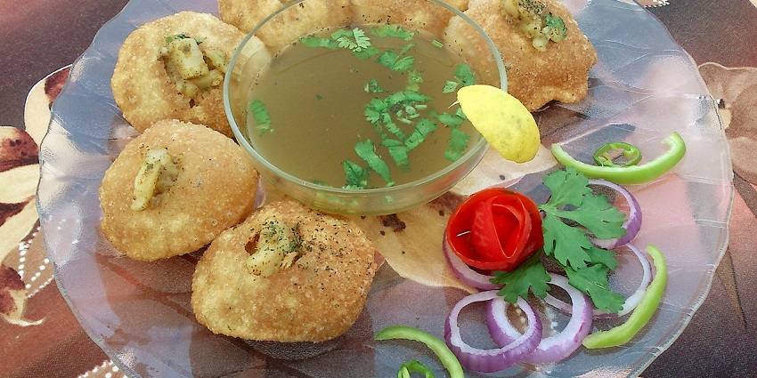 Snapshot of the crispy pani puri in the glass plate served on the table with salty sauce