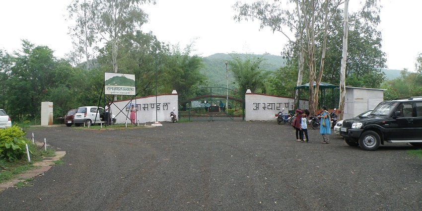 The entrance to Ralamandal Wildlife Sanctuary with a sign, a gate, and parked vehicles