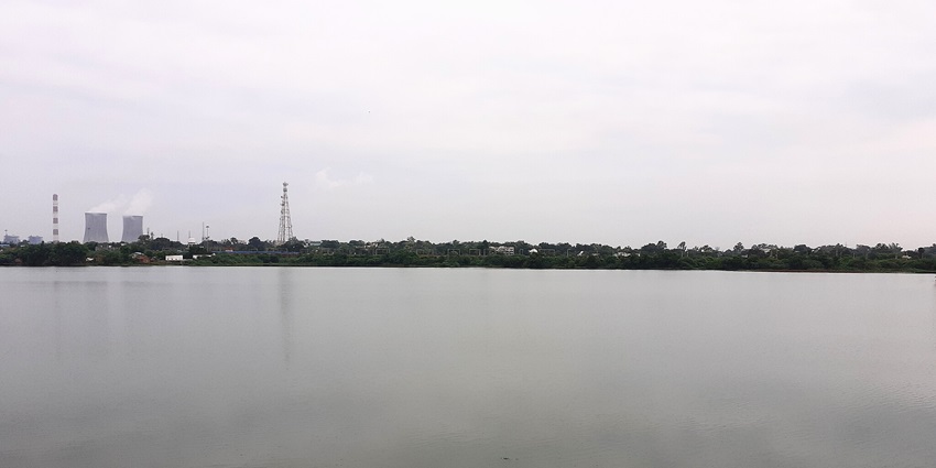People relaxing by Ramala Talao Lake surrounded by greenery.