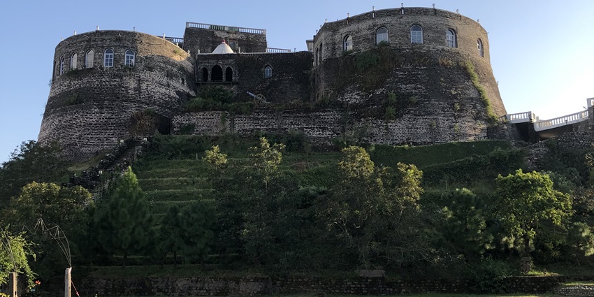 Scenic image of a palace by the river side amidst the beautiful dense jungle and tress