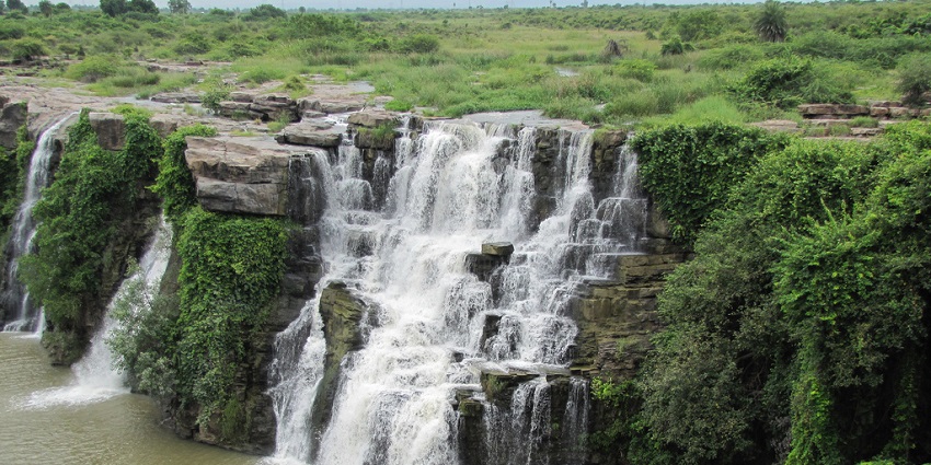 Silver water cascading down the rocks into the serene pool surrounded by lush greenery