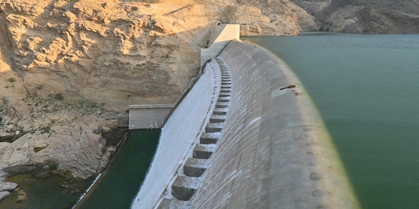 A scenic view of the Ranakpur Dam surrounded by rugged terrains and rolling hills.