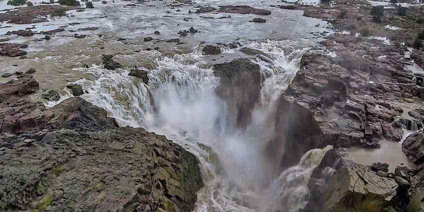 Volcanic rock formations at Raneh Falls with water cascading in multicoloured hues.