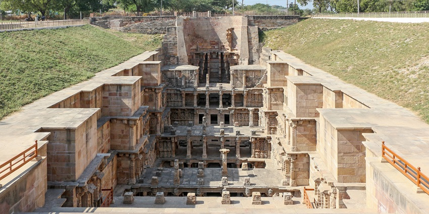 A picture of a historical stepwell near Deesa, Gujarat with intricate wall carvings throughout the depths