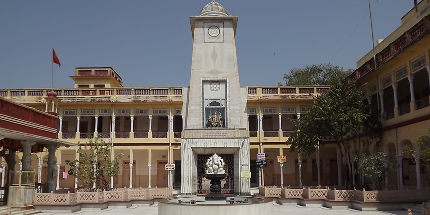 A picture of an inner courtyard of a temple with a pillar standing tall in the middle