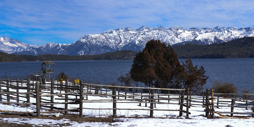 A picture of a lake in Nepal with a range of snow-capped mountains visible in the background at a distasnce
