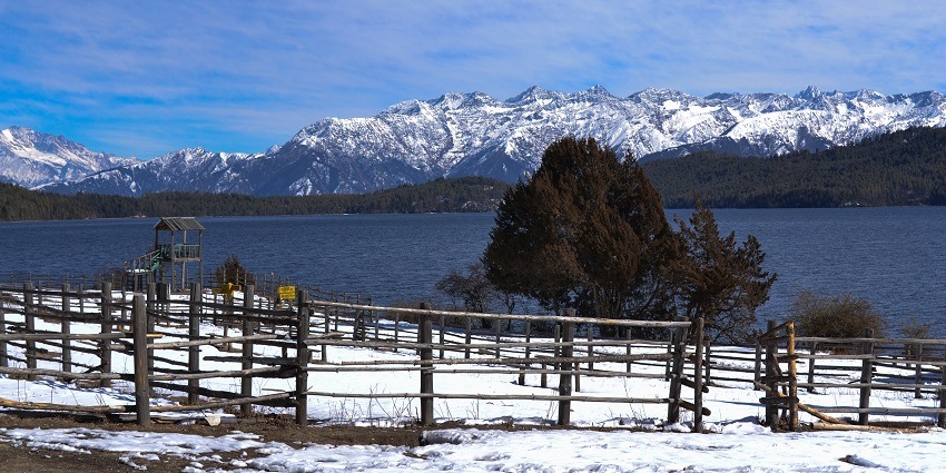 A picture of a lake in Nepal with a range of snow-capped mountains visible in the background at a distasnce