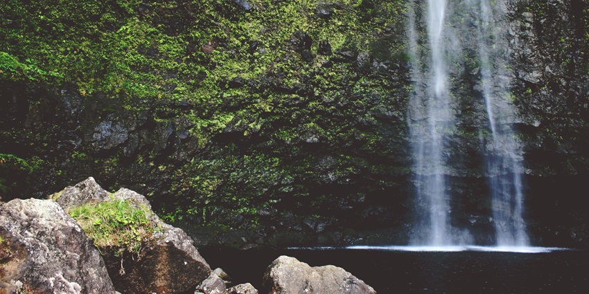 An image of Ravana falls surrounded by greenery and rocky cliffs in Sri Lanka.