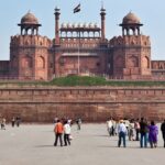 A frontal picture of a fort in Delhi with Indian Flag hoisting on the top and tourists admiring the views