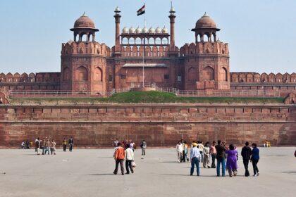 A frontal picture of a fort in Delhi with Indian Flag hoisting on the top and tourists admiring the views