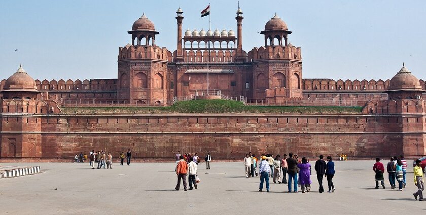 A frontal picture of a fort in Delhi with Indian Flag hoisting on the top and tourists admiring the views