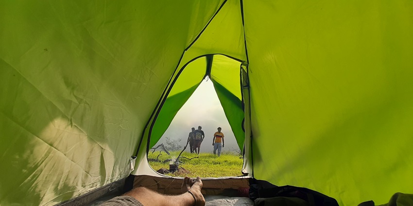 A scenic riverside campsite in Dandeli, surrounded by lush forests and a glowing bonfire under the starry sky.