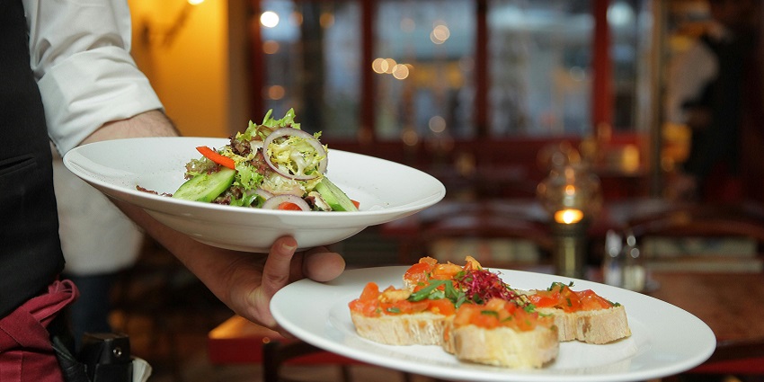 A person serving dishes in a restaurant with a beautiful setting and tranquil environment