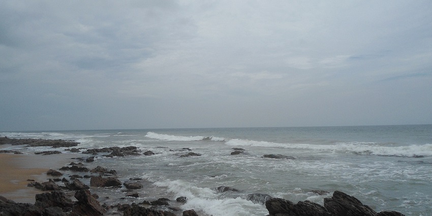Majestic view of waves crashing the rocky shores of Rishikonda beach under a cloudy sky