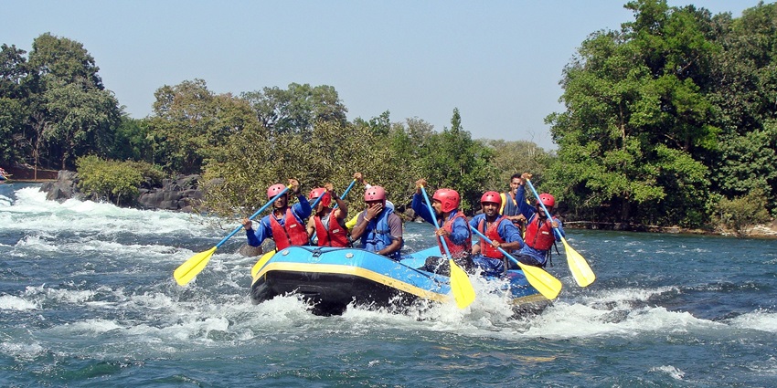 Group of people river rafting on the white waters of the Kali River amid the Western Ghats.